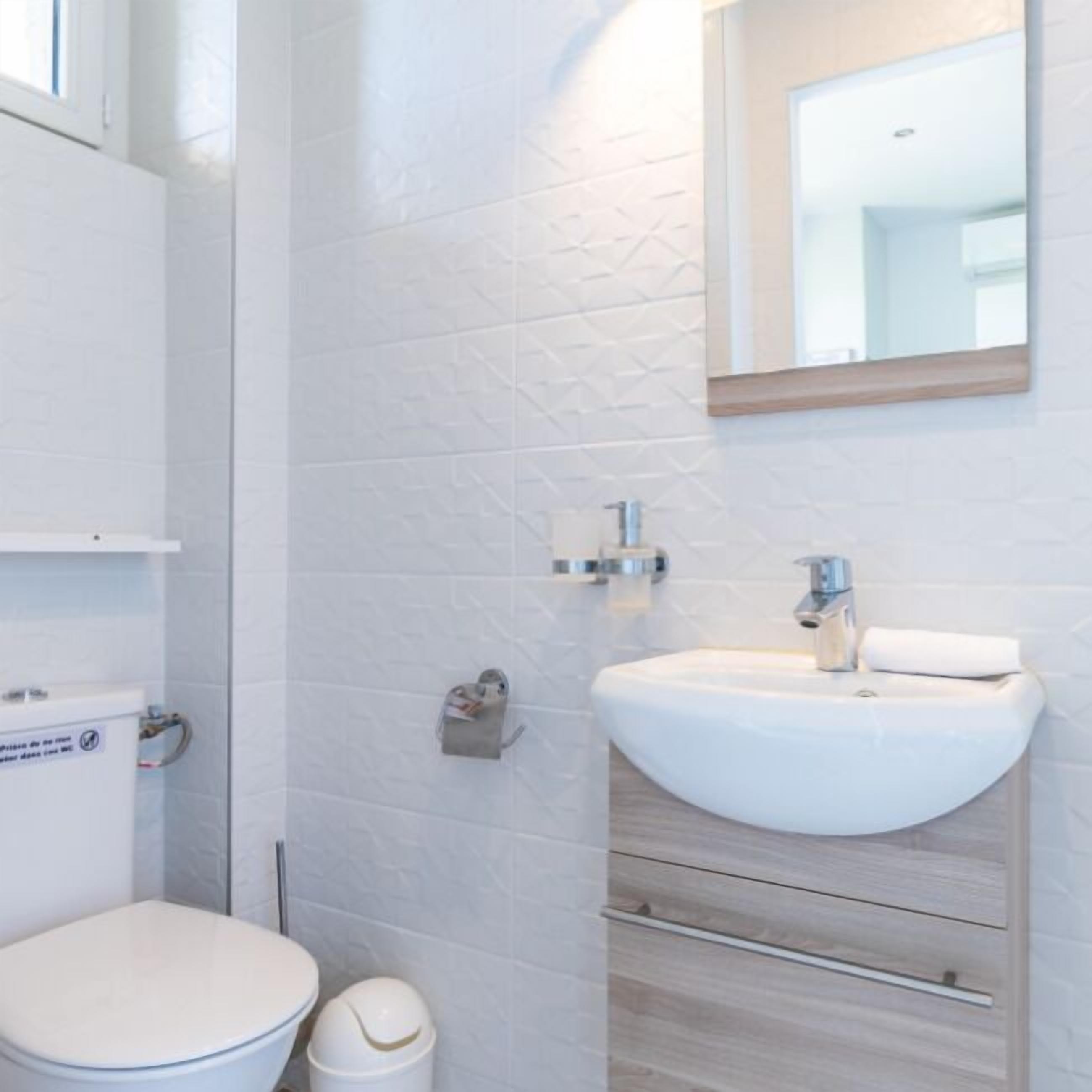 Un baño moderno con inodoro, lavabo y espejo.
