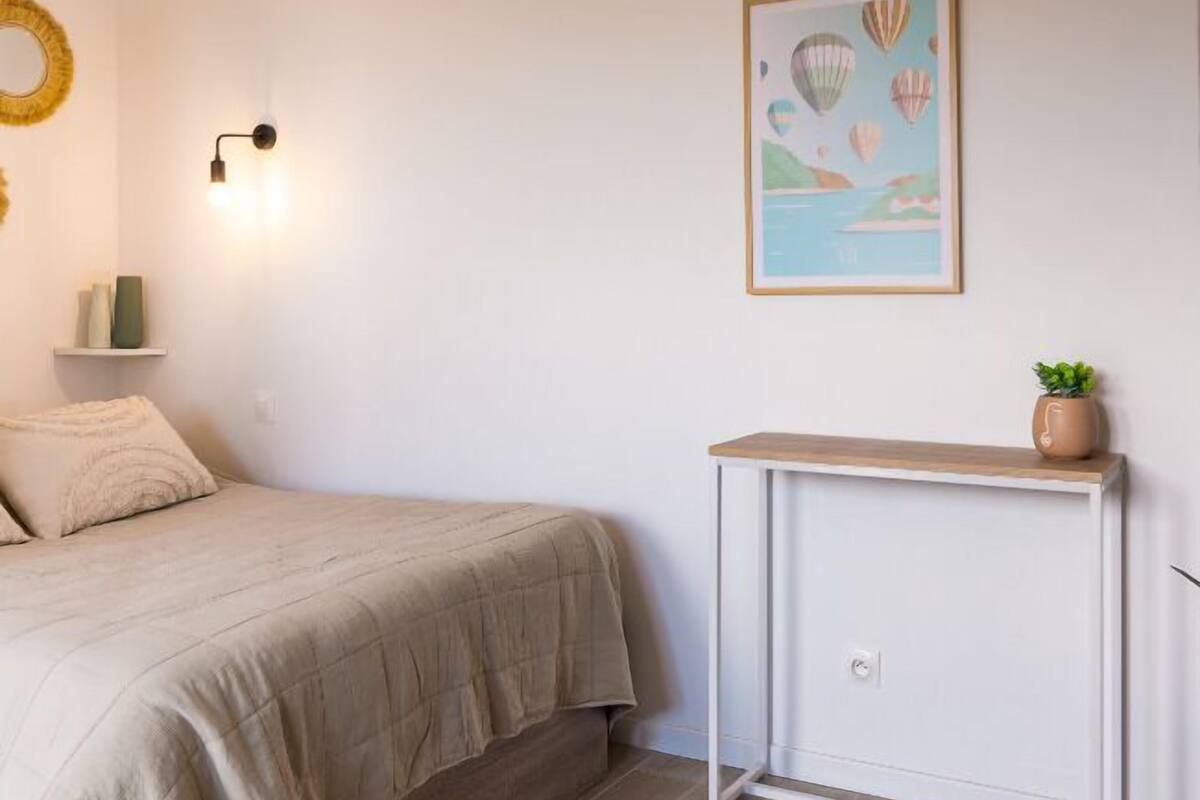 A bedroom with a bed, bedside table, and a wall-mounted light fixture.