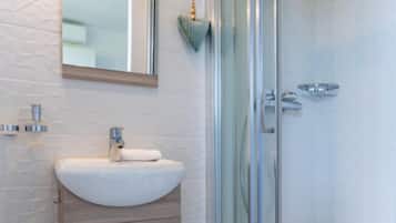 A modern bathroom with a white sink, wooden cabinet, and a glass shower enclosure.