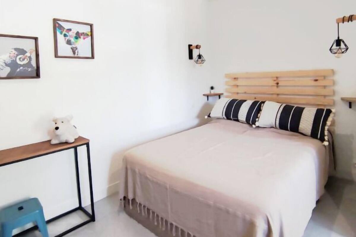 A minimalist bedroom with a bed, a desk, and a chair.