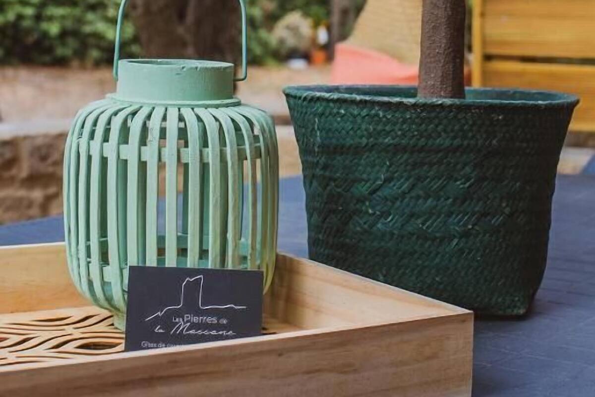A small potted plant and a green lantern on a wooden table outdoors.