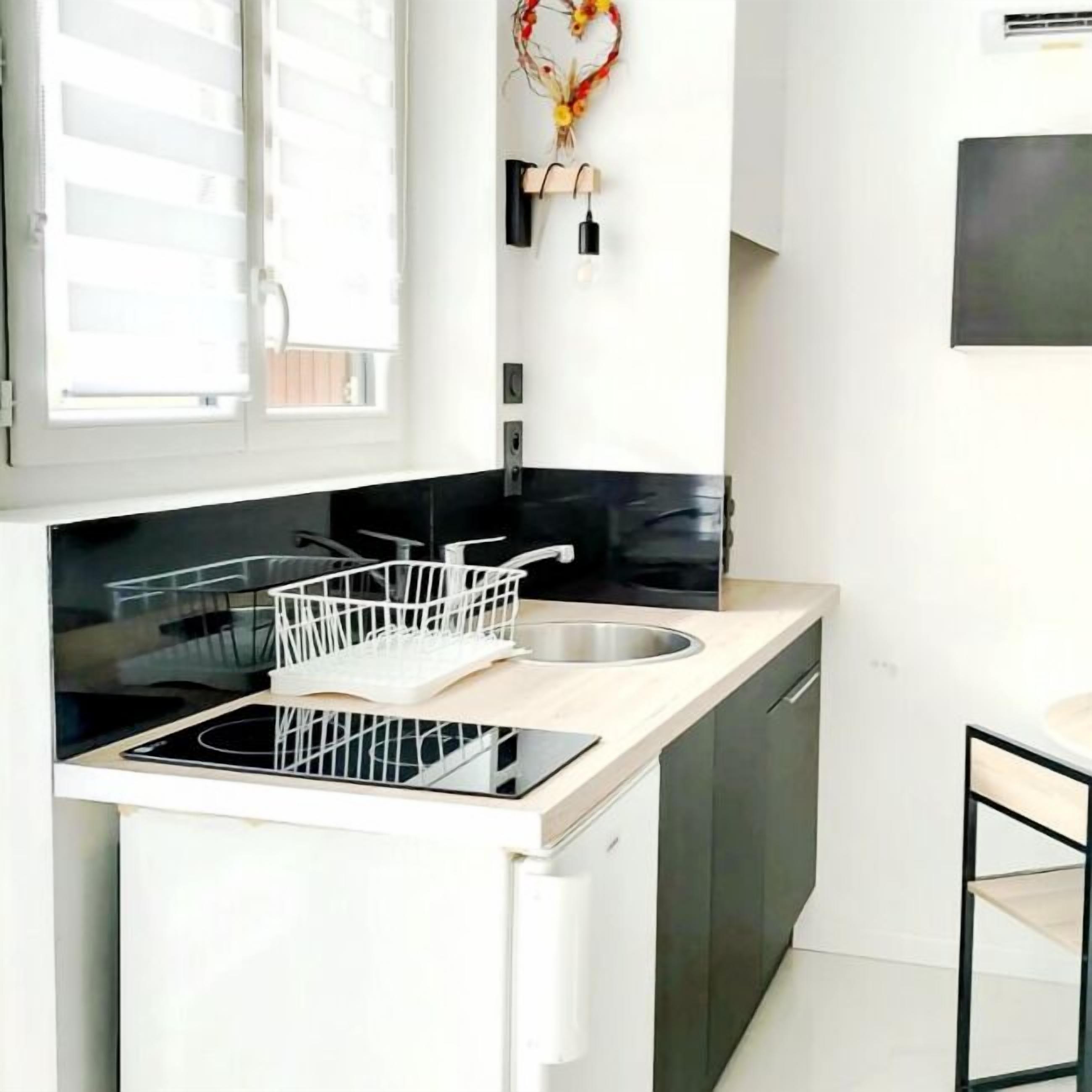 A modern kitchen with a black stovetop, white cabinetry, and a white countertop.