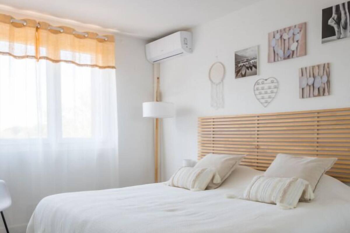 A bedroom with a large bed, a bedside table, a lamp, and artwork on the wall.