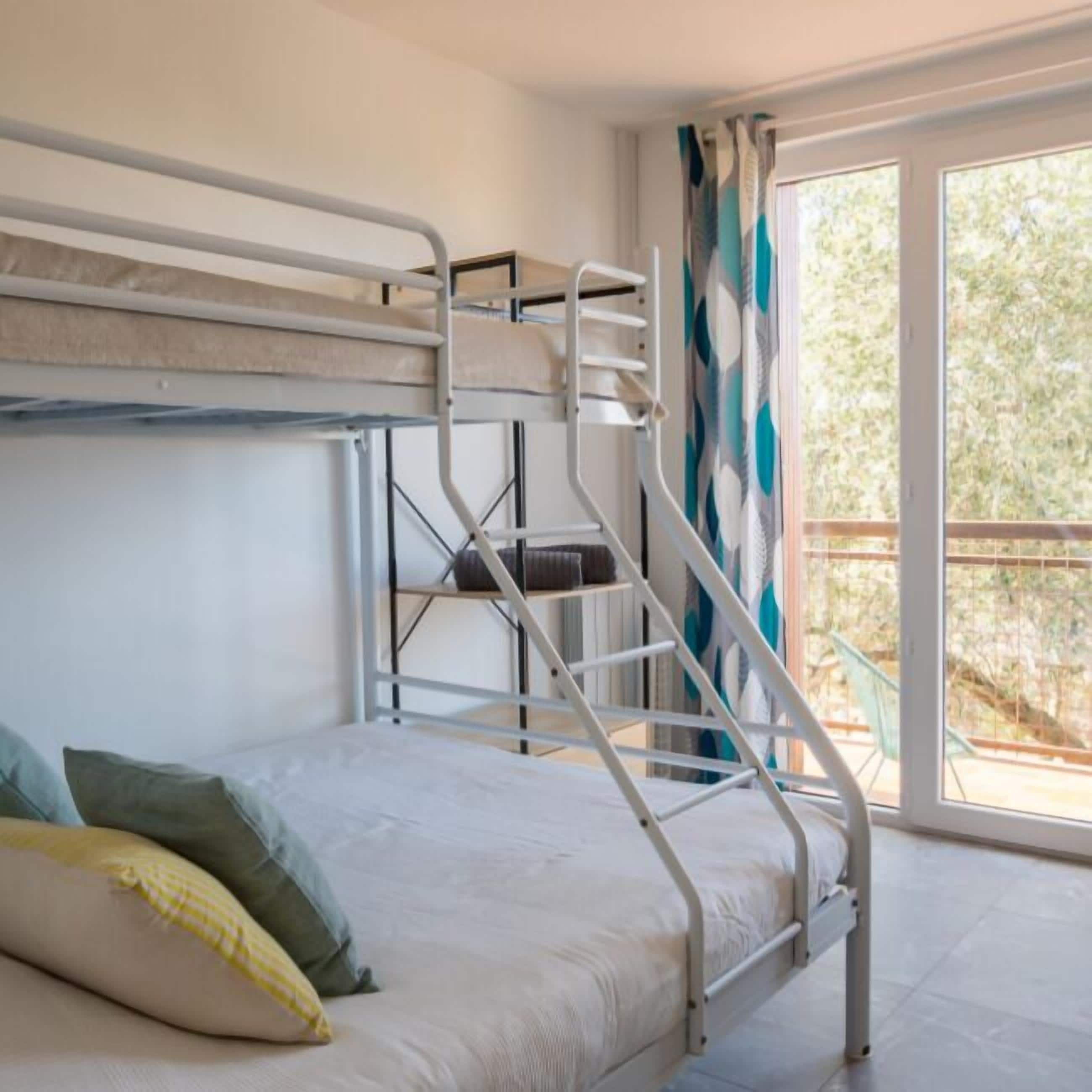A bunk bed room with a window and curtains.