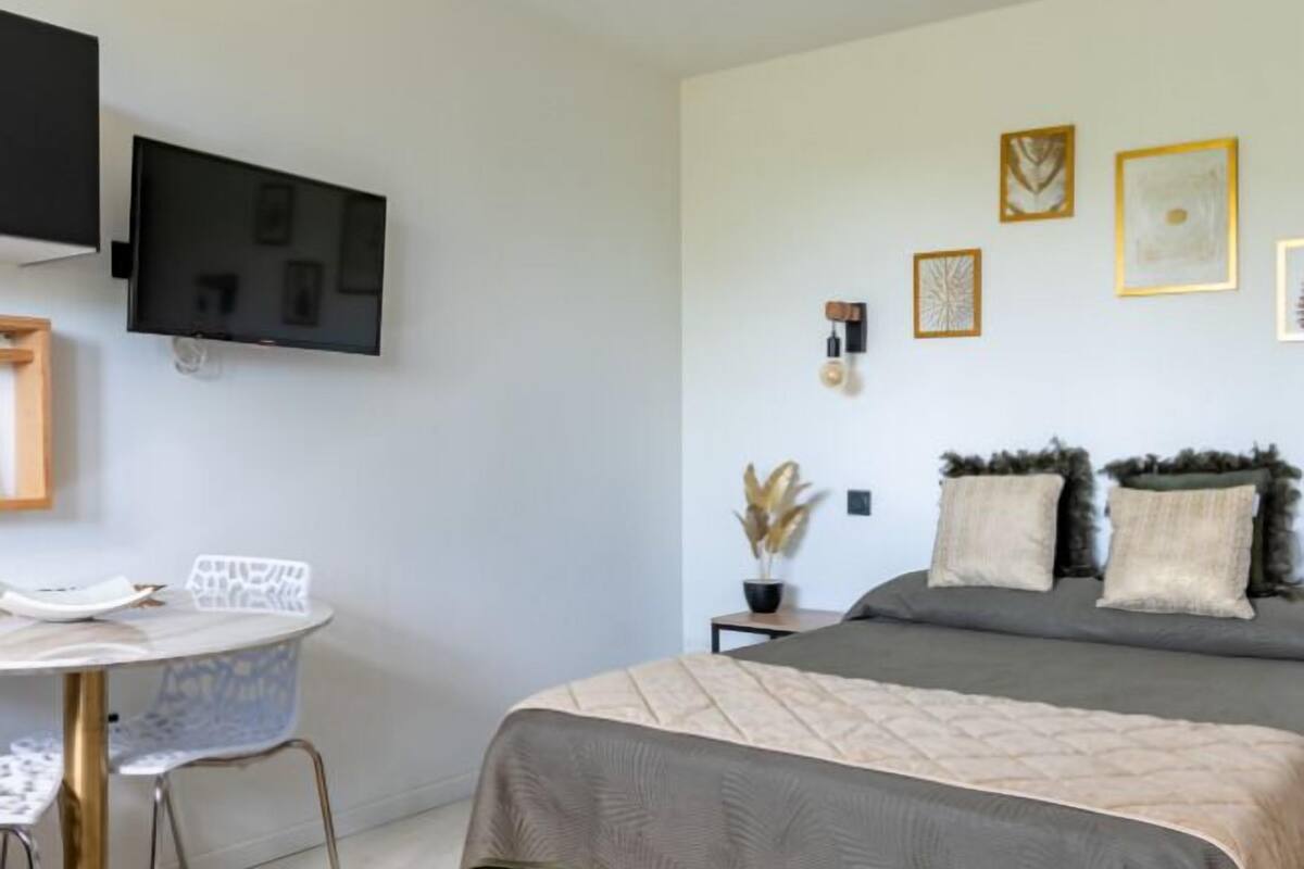 A modern bedroom with a bed, a desk, and a TV.