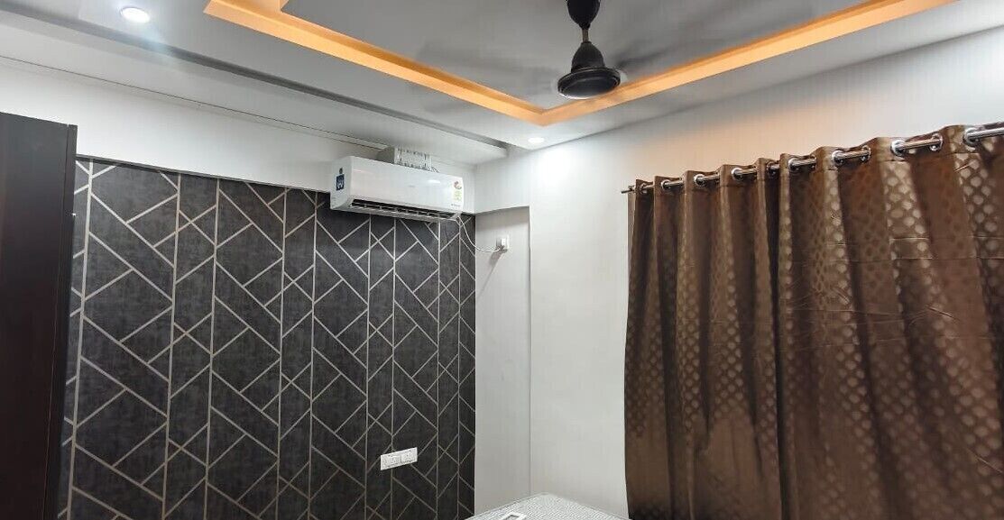 A bathroom with a geometric-patterned wall, a ceiling fan, and a shower curtain.