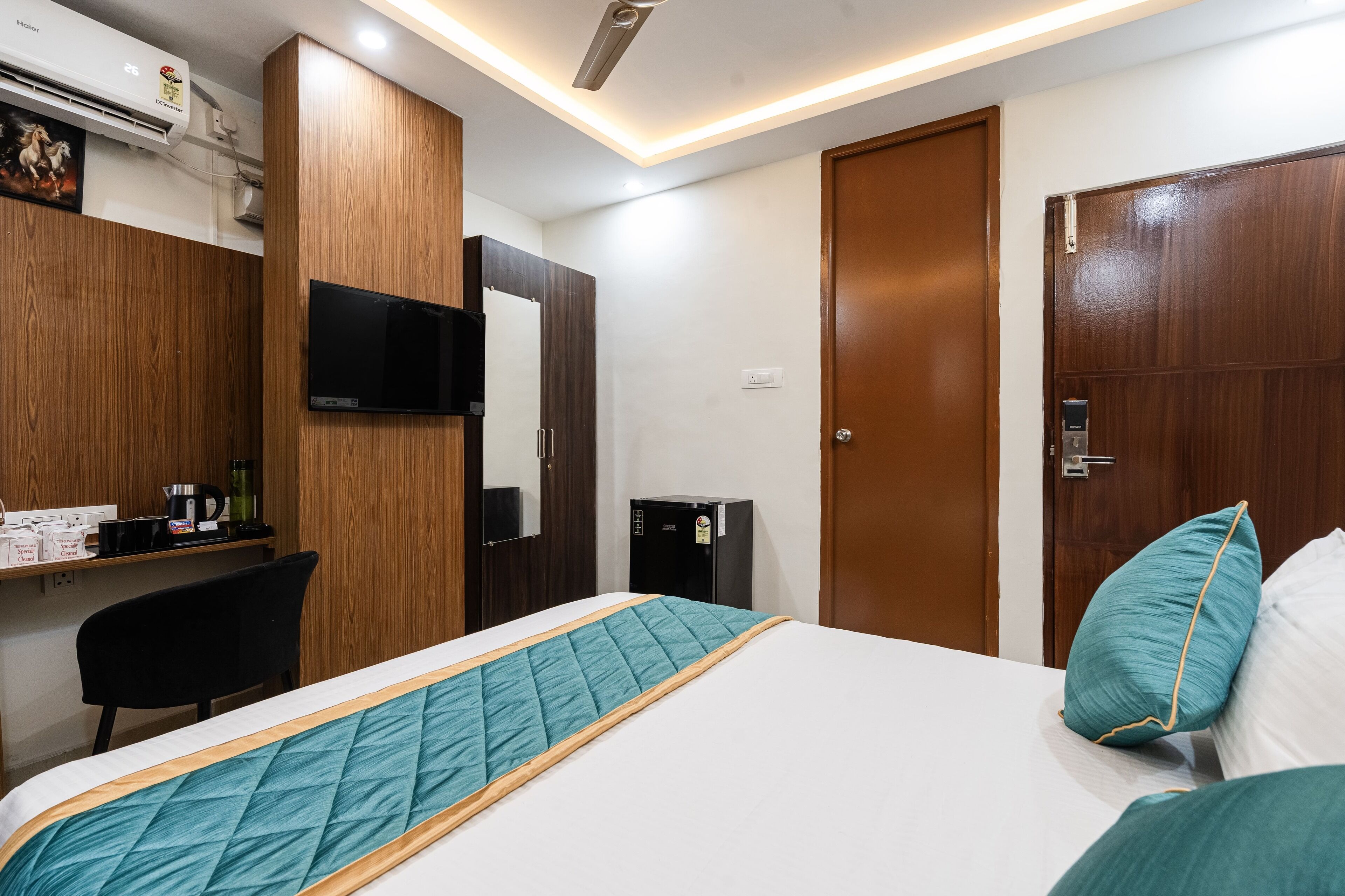 Un dormitorio con cama, escritorio, silla, televisor y armario.