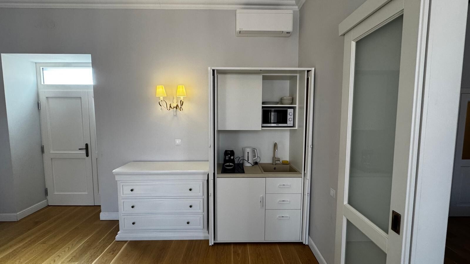 A compact kitchen with a microwave, sink, and cabinets.