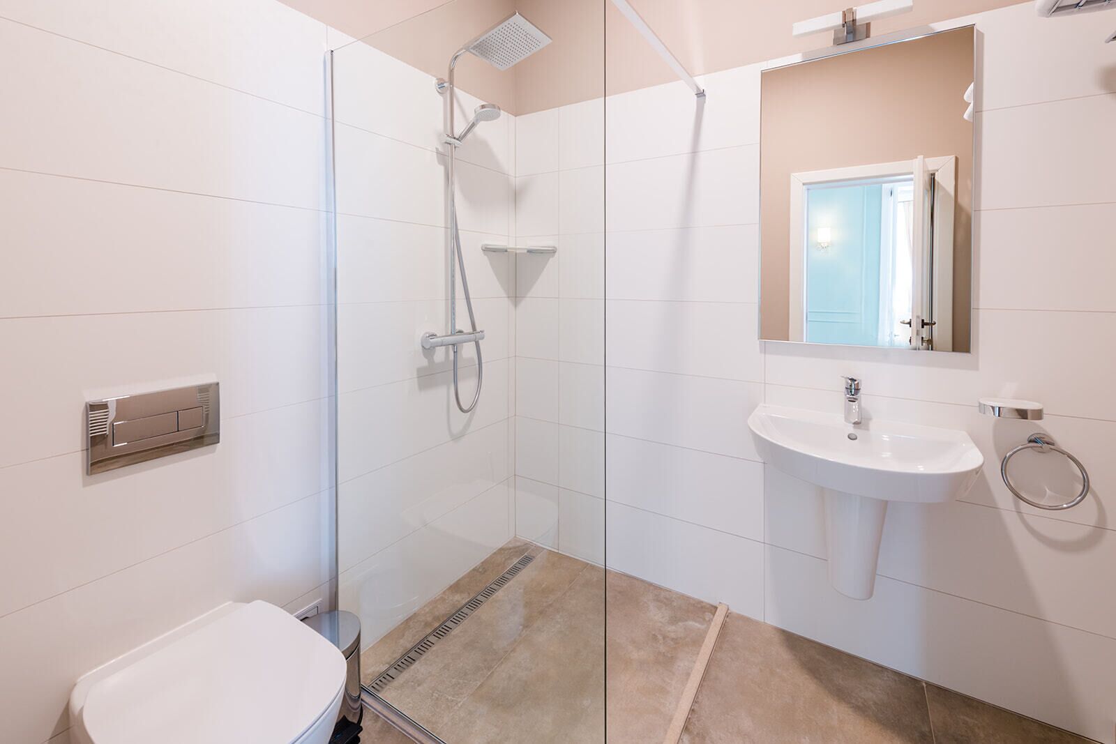 A modern bathroom with a glass-enclosed shower, a pedestal sink, and a toilet.
