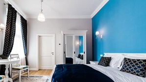 A bedroom with a bed, a desk, and a chair. There is a door and a mirror. - Casa Petra (Sibiu)