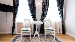 A room with two white chairs, a small white table, and a patterned rug. - Casa Petra (Sibiu)