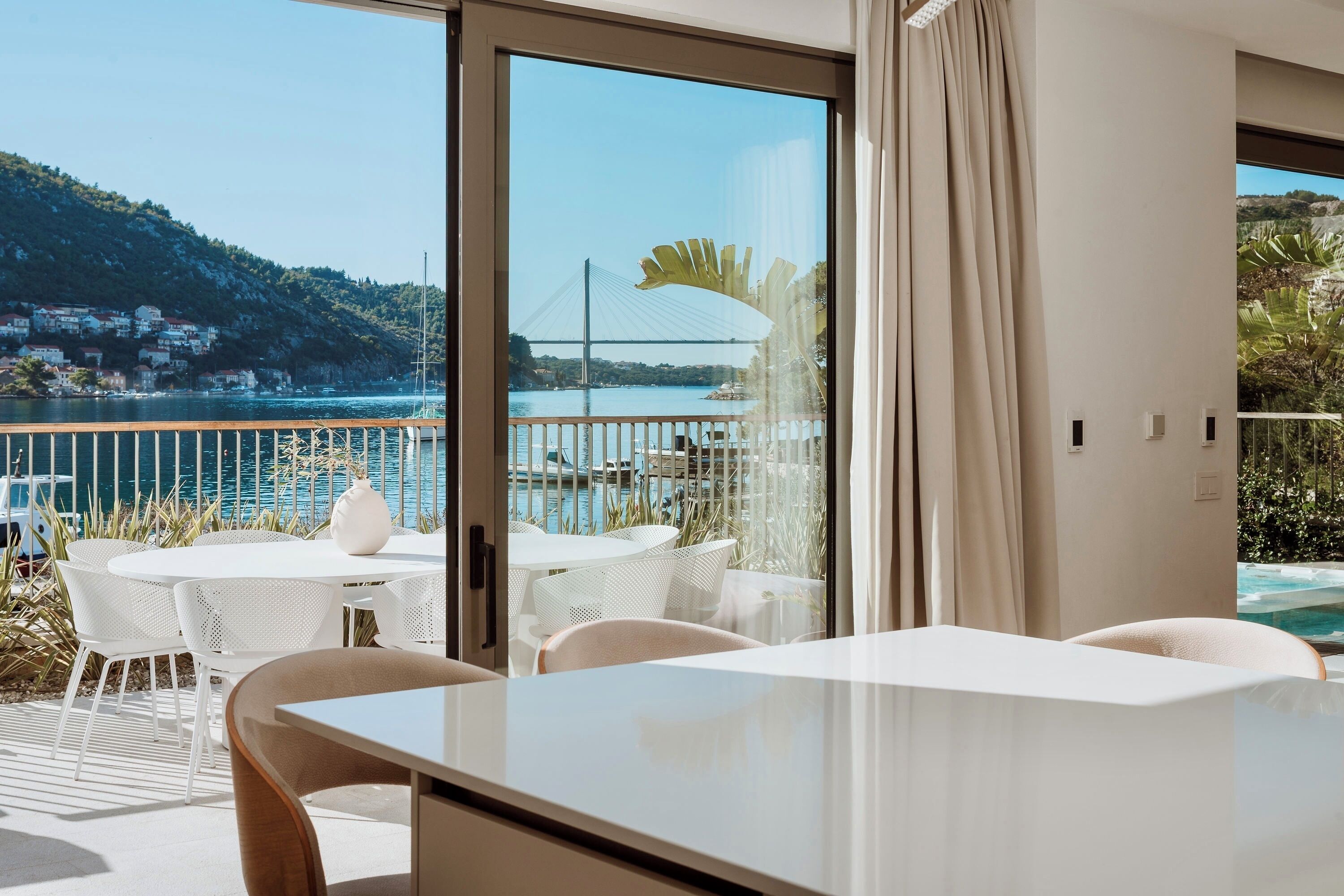 Un balcón con una mesa y sillas, vista a un puente y una piscina.