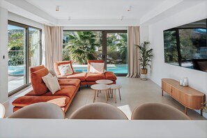 A modern living room with a sectional sofa, round coffee table, and a TV mounted on the wall. - Villas & Spa Dubrovnik (Dubrovnik)
