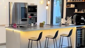 Una cocina moderna con una isla central, taburetes de bar y una cafetera.