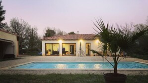 A house with a swimming pool, a patio with outdoor furniture, and a potted plant.