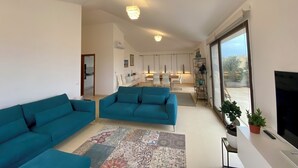 Ein modernes Wohnzimmer mit taubenblauen Sofas, einem gemusterten Teppich und einem großen Fernseher.