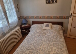 Cozy retreat with a neatly made bed, bedside table, and radiator, perfect for a restful stay.