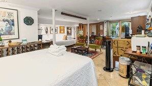 Een hotelkamer met een groot bed, een bureau met een computer, een stoel, een klein tafeltje en een raam met uitzicht.