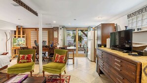Een moderne woonkamer met een bank, stoelen, een salontafel en een televisie.