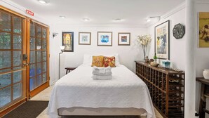 Een hotelkamer met een bed, een houten deur, een wandklok en lijstjes met foto's.