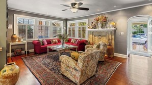 A living room with a red sofa, patterned armchairs, a coffee table, and a fireplace. - La Petite Fleur Rouge | Elegant & Cozy 2/1 Getaway (North Charleston)