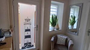 A room with a wooden ceiling, a door with a view of a building, a potted plant, a chair, and a mirror on the wall. - Vacation home Zastrow in Kappeln-Olpenitz (Kappeln)