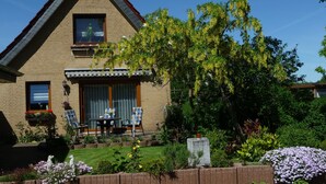A two-story house with a brick facade, a small balcony, and a garden with various plants and flowers. - Vacation home Zastrow in Kappeln-Olpenitz (Kappeln)