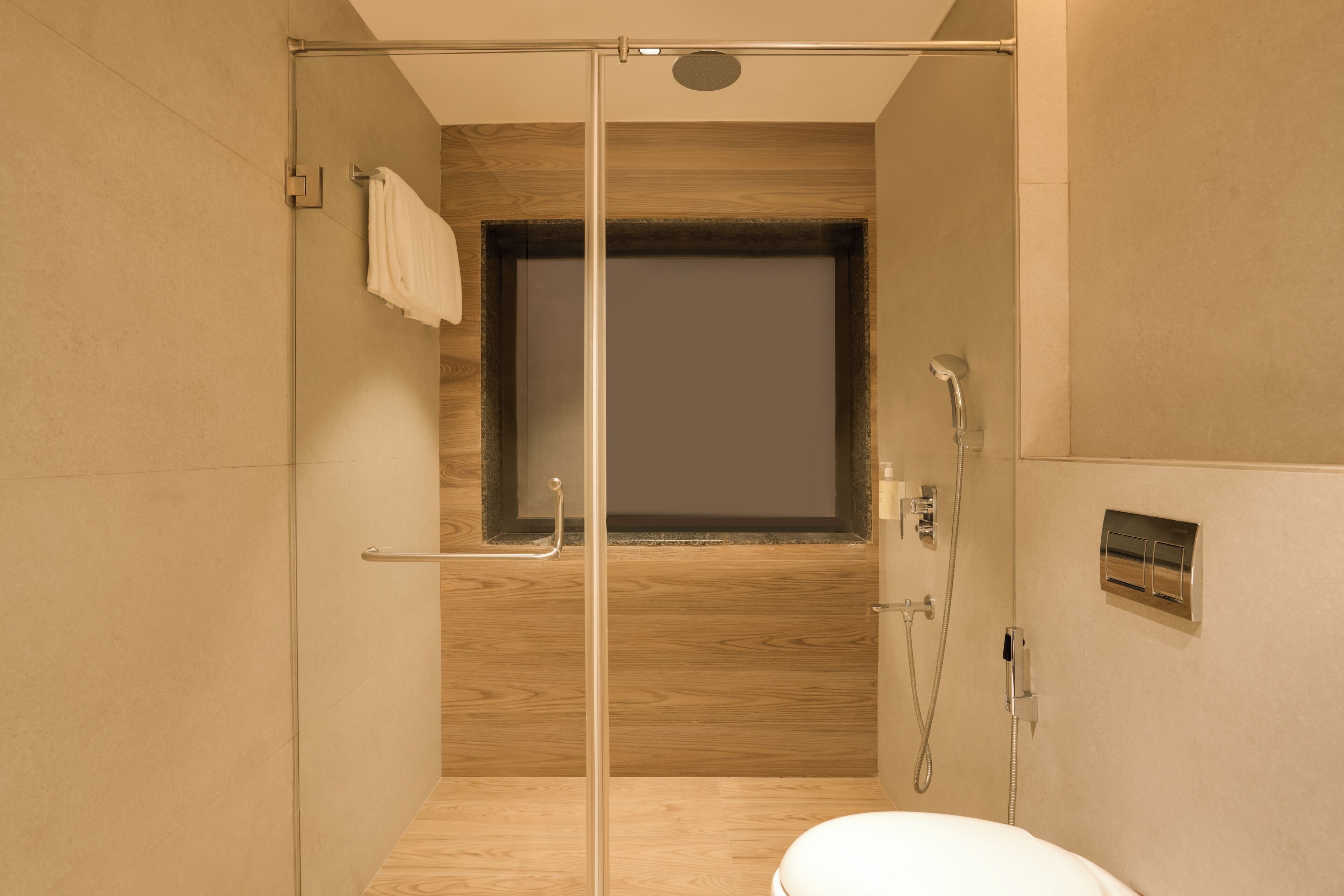 A modern bathroom with a glass shower enclosure, a wooden vanity, and a toilet.