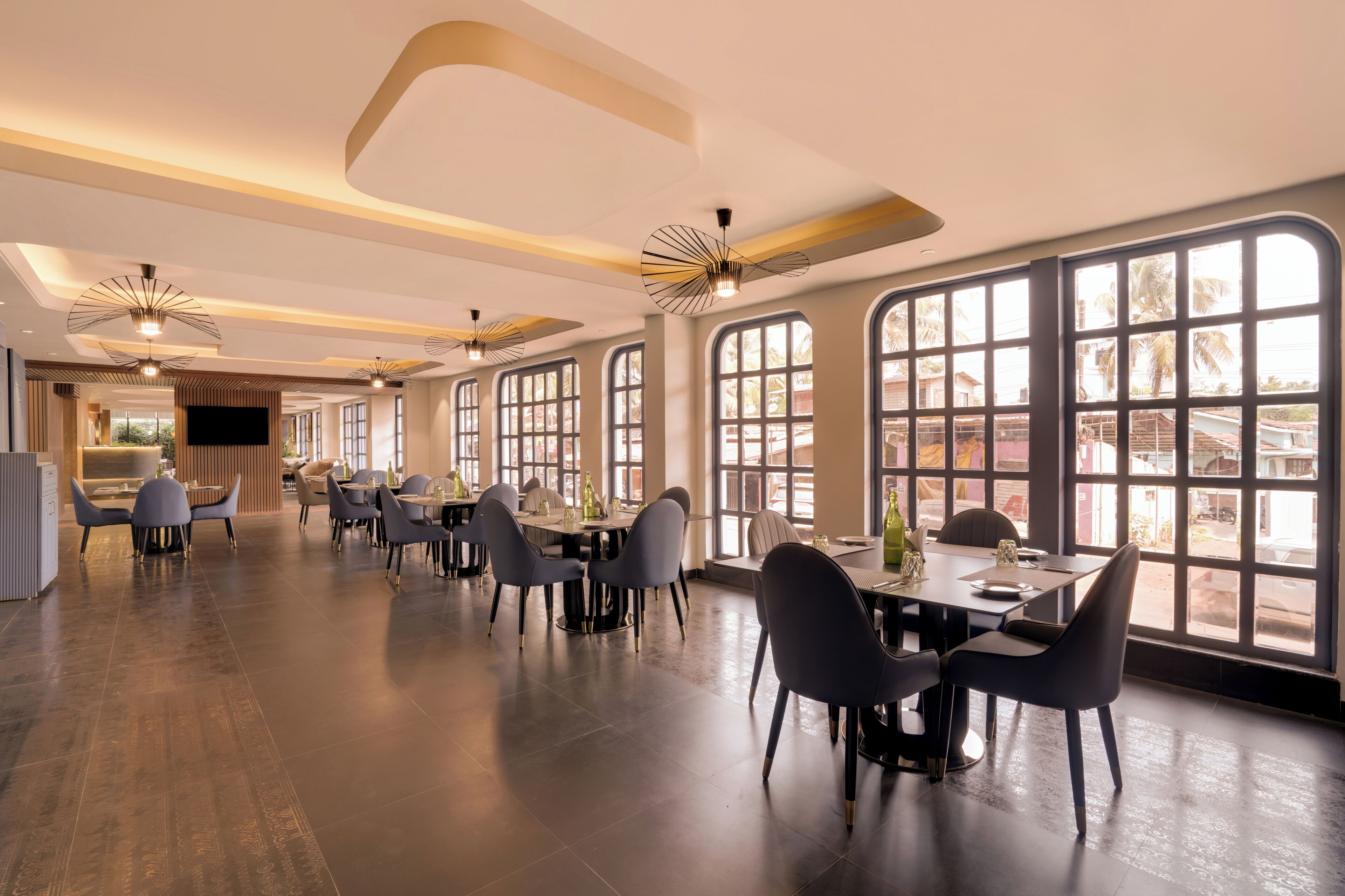 Un amplio comedor con techos altos, ventanas grandes e iluminación moderna.