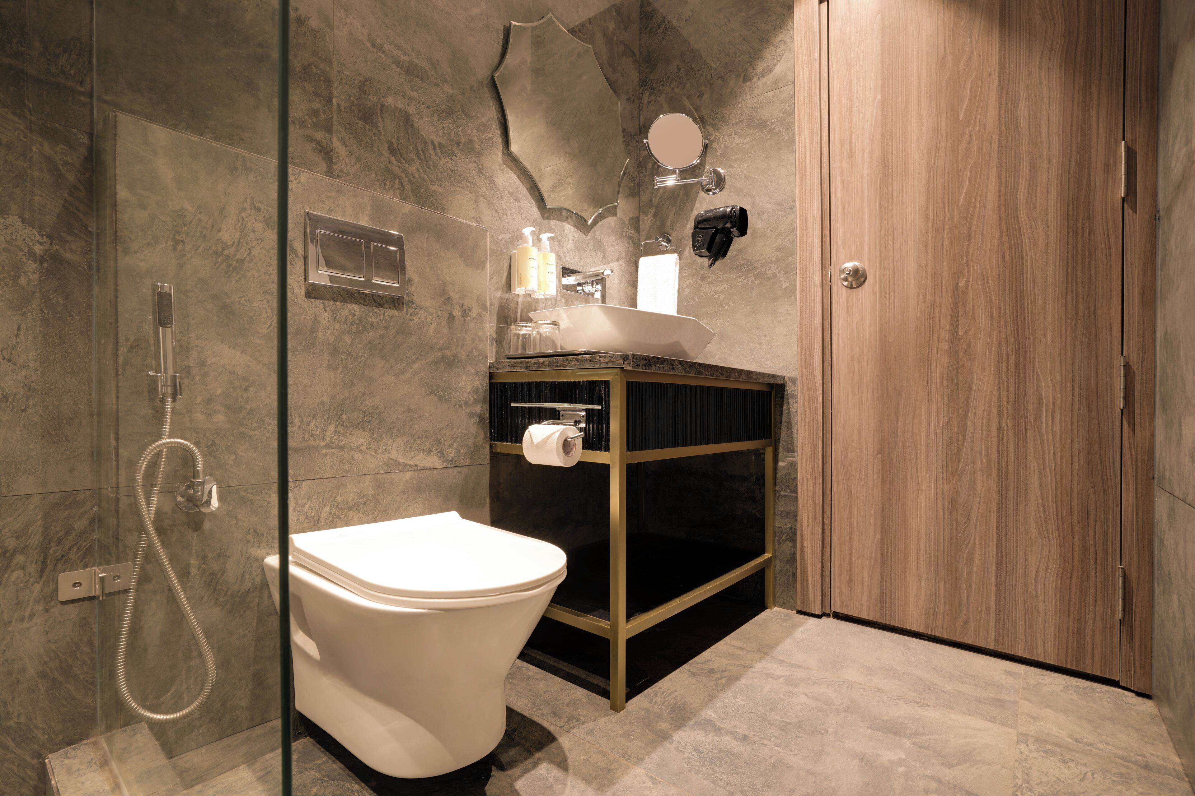A modern bathroom with a glass-enclosed shower, a white toilet, a wooden vanity with a sink, and a mirror.
