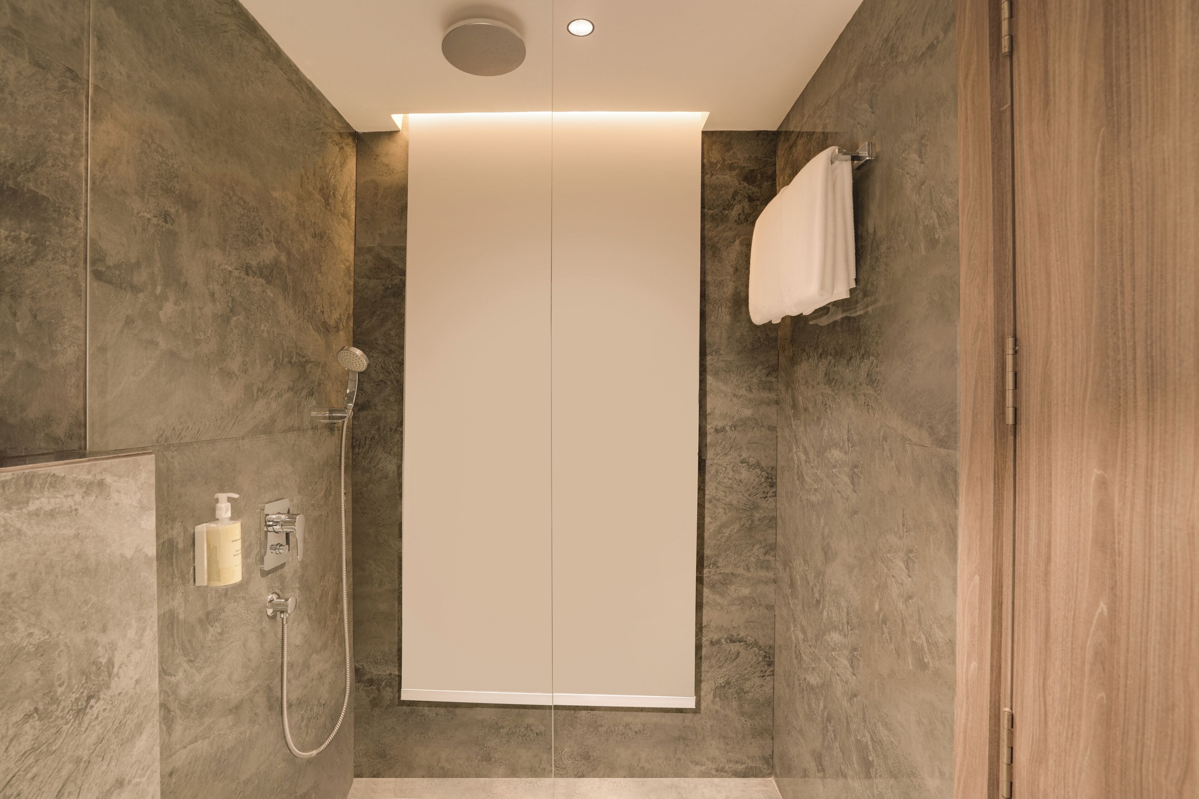 A modern bathroom with a walk-in shower, a towel rack, and a built-in toilet.