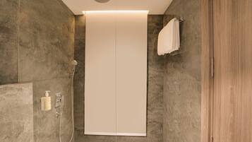 Ein modernes Badezimmer mit bodenebene Dusche, Handtuchhalter und integriertem WC.