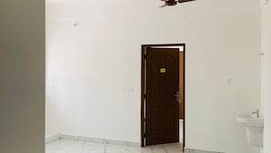 A spacious room with a marble floor, a ceiling fan, and a door marked with a number. - Celestia residency (Kanayannur)