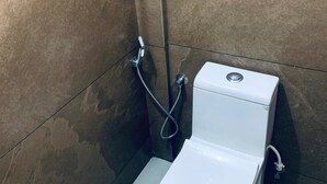 A small, modern bathroom with a white toilet, a shower, and a wall-mounted sink. - Celestia residency (Kanayannur)