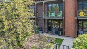 Ein mehrstöckiges Gebäude mit Außenbereichen, darunter grüne Adirondack-Stühle und ein Grill.