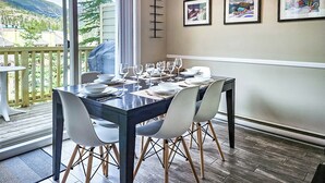 A dining area with a table set for four, a sliding glass door leading to a balcony, and three framed artworks on the wall. - Ski-In/Ski-Out Mountain Retreat / Hot Tub + Garage (Panorama)