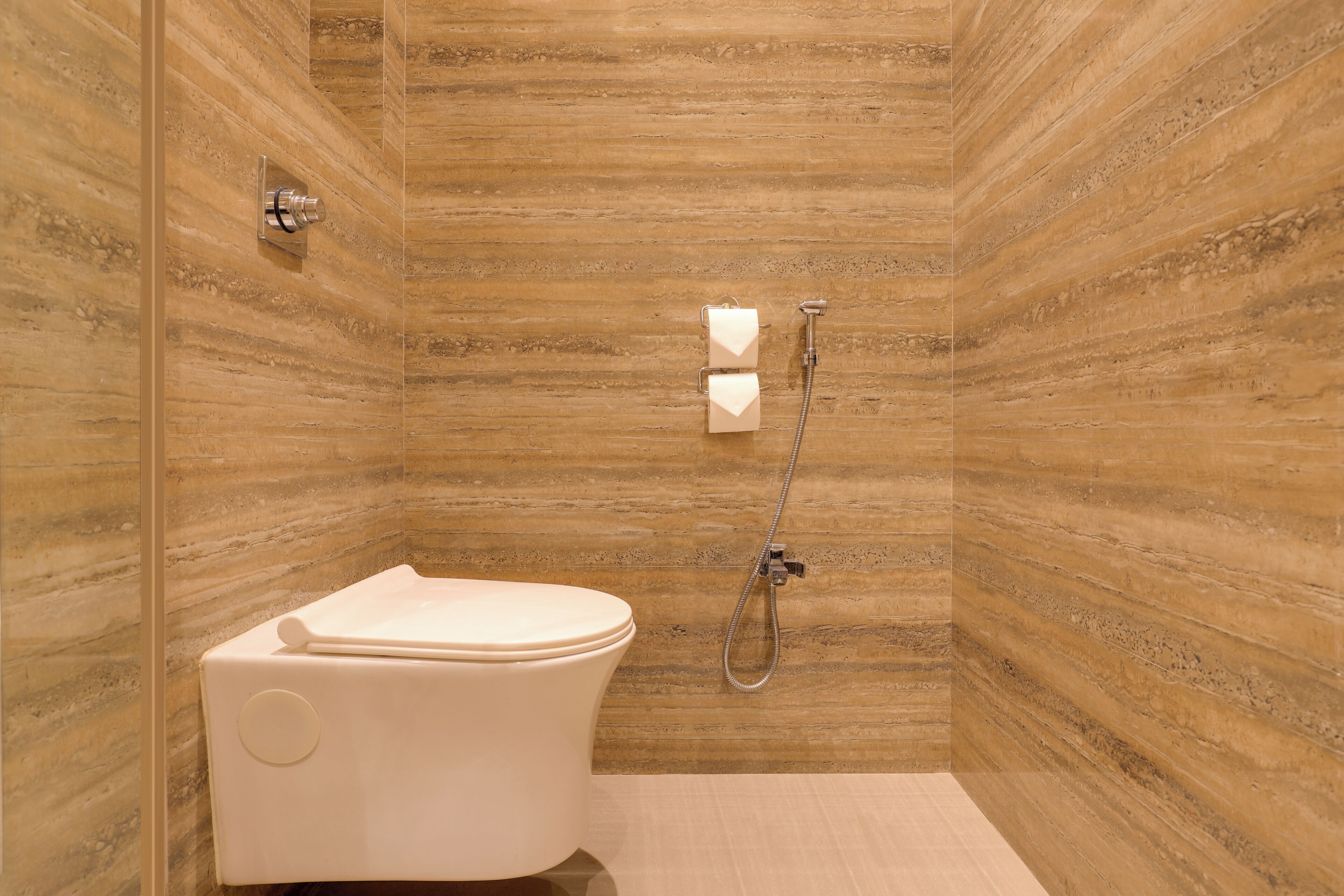 Une salle de bain avec des toilettes, une douche et un mur en marbre.