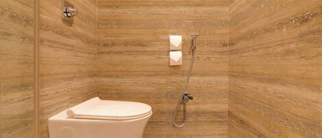 Une salle de bain avec des toilettes, une douche et un mur en marbre.