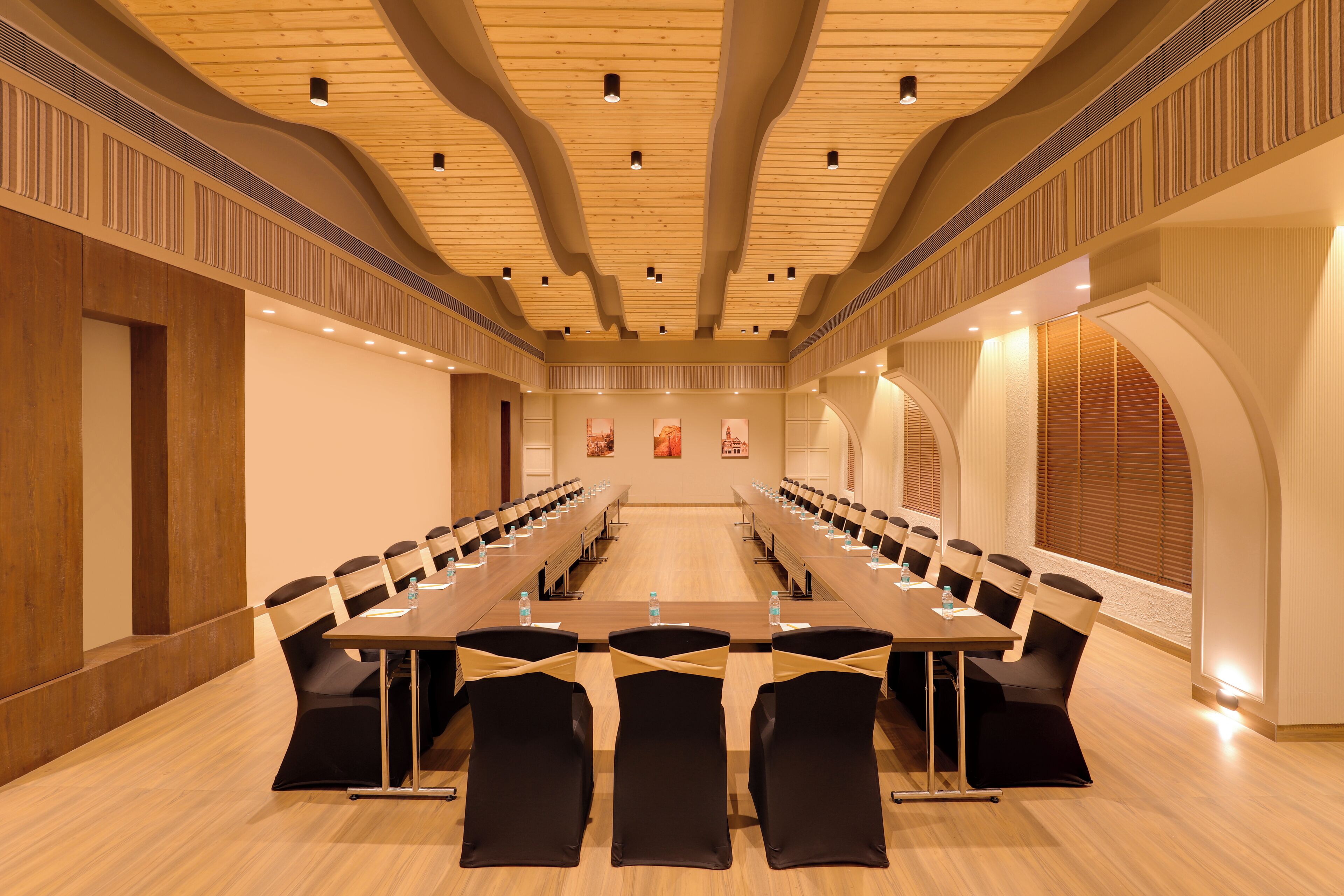 Un salón de conferencias con una larga mesa y sillas, techo de madera e iluminación empotrada.