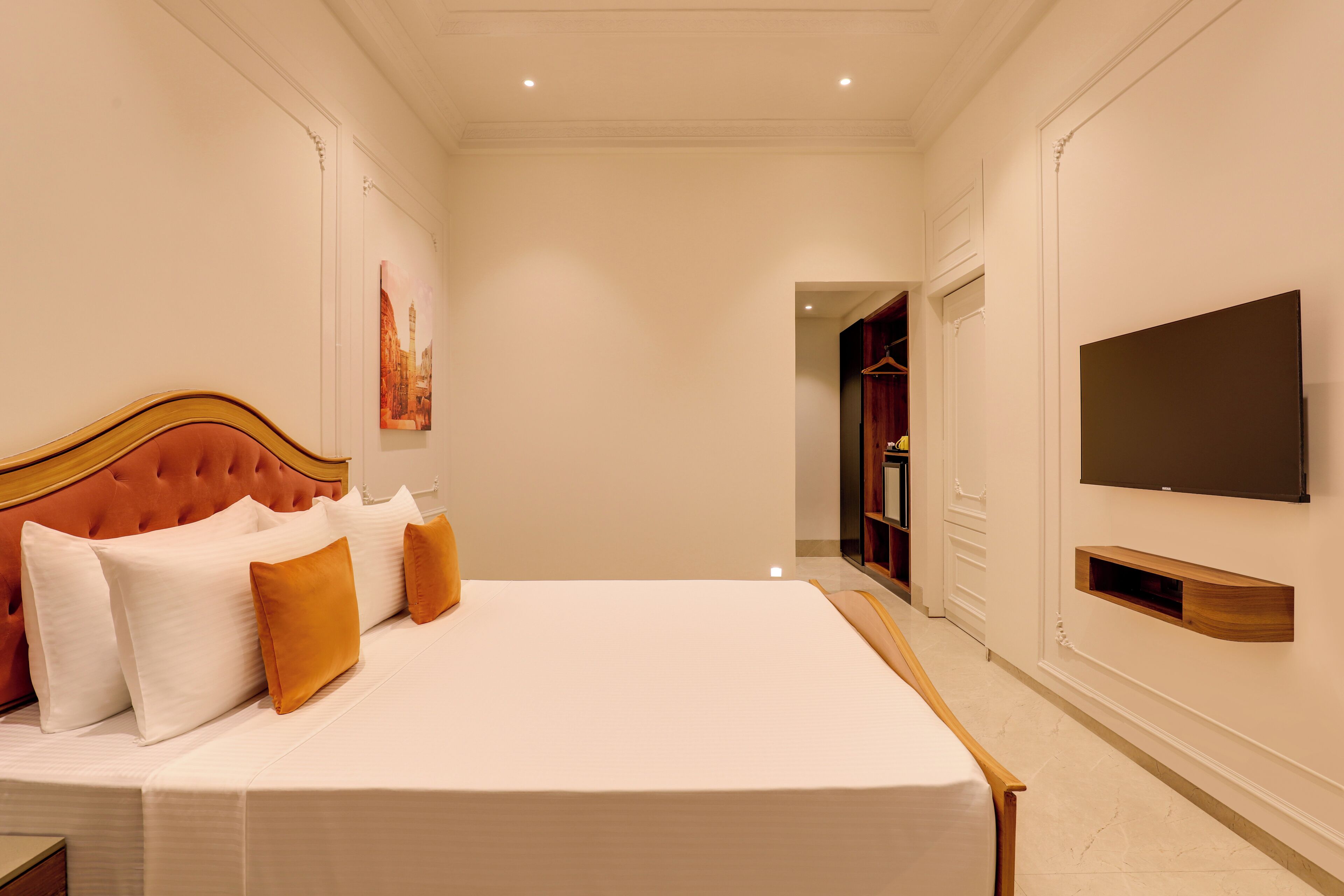 Una habitación de hotel con una cama grande, un televisor de pantalla plana en la pared y un armario.