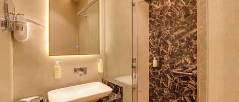 A bathroom with a marble sink, a glass shower enclosure, and a mirror above the sink.