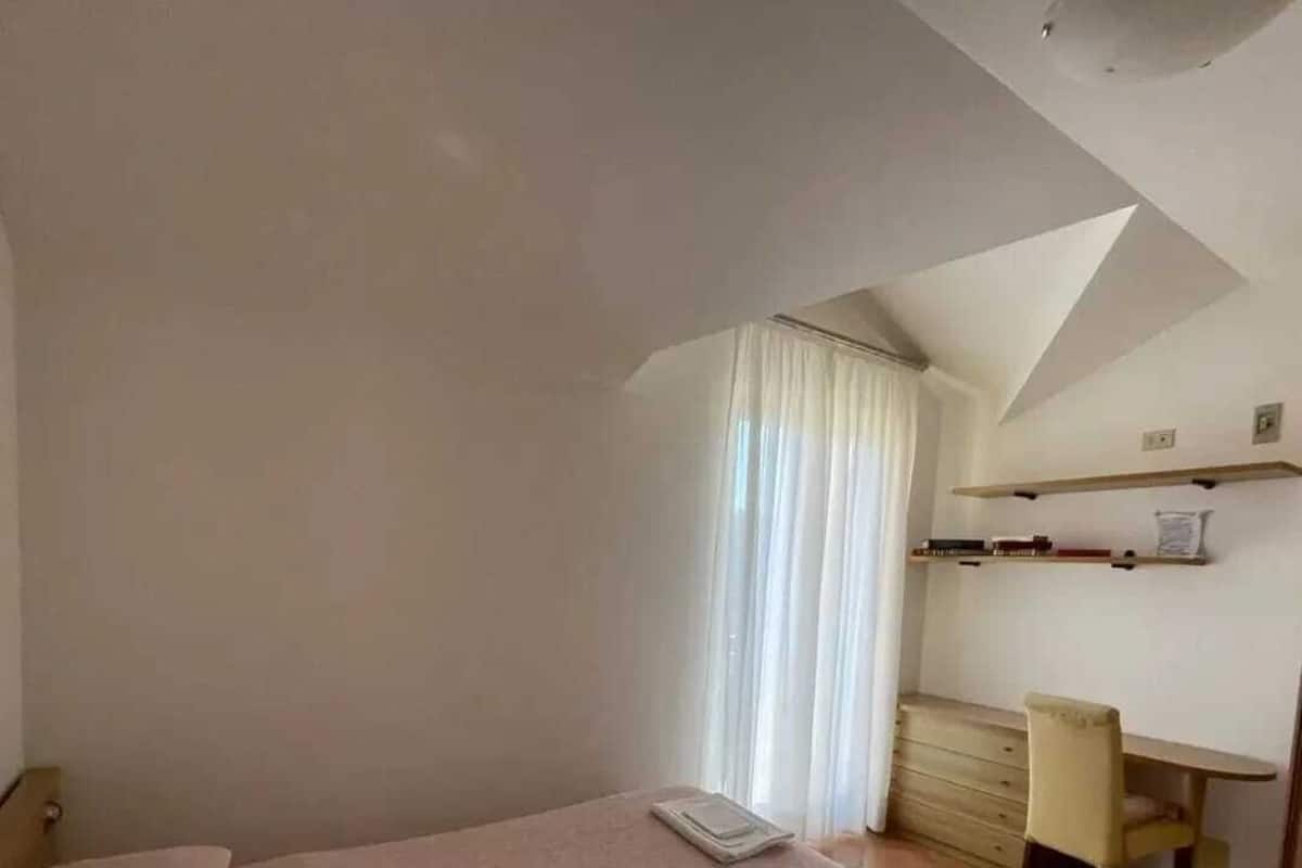 Un dormitorio con cama, escritorio, silla y ventana con cortinas.