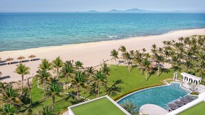 A resort with a pool, beach, and palm trees.
