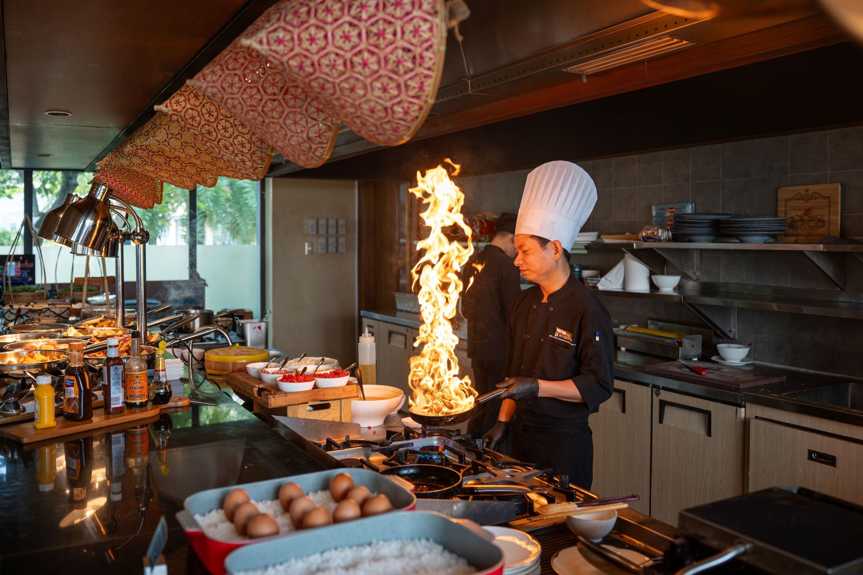 A chef cooking with flames, a buffet with various dishes, and kitchen equipment.