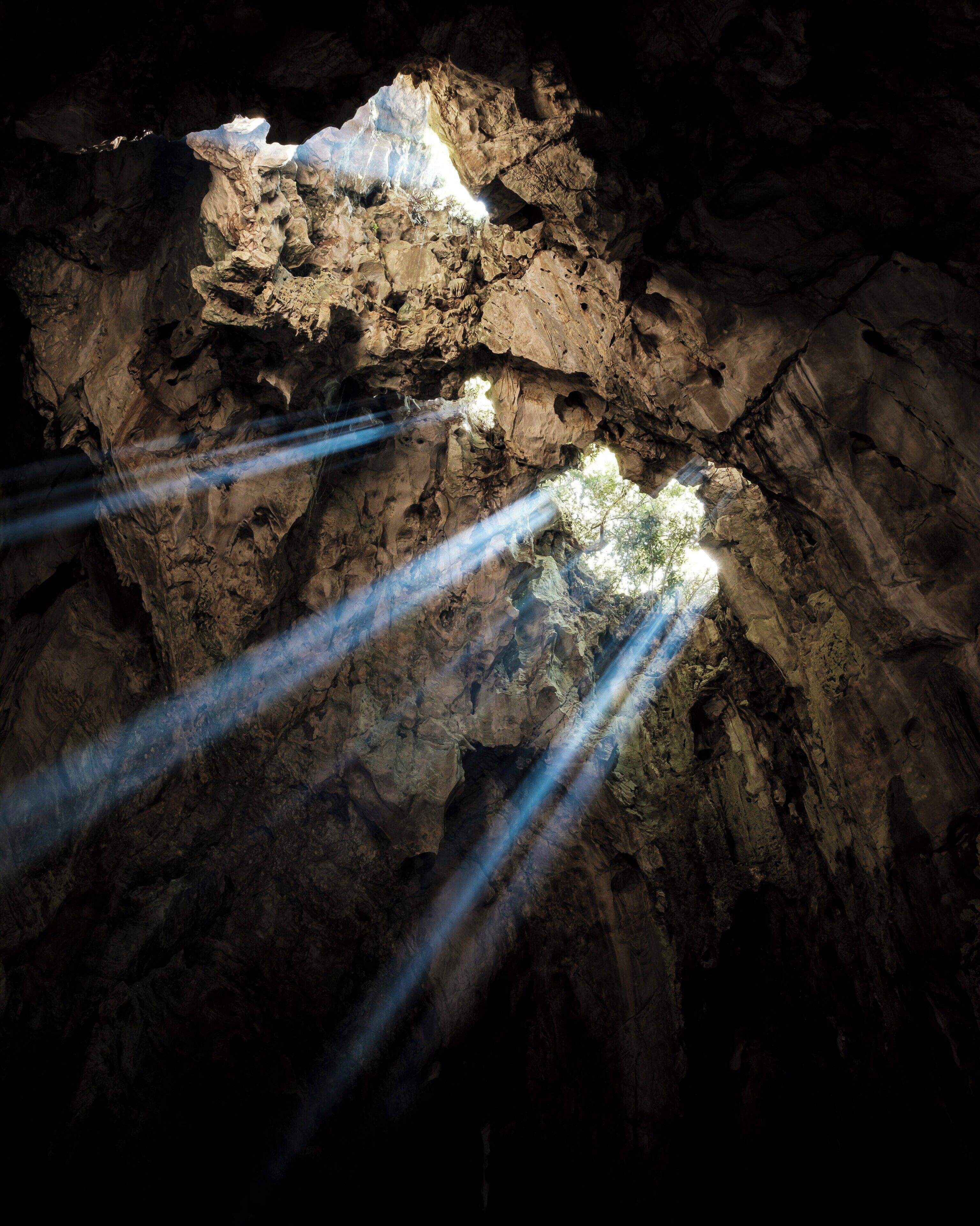 A cave interior with natural rock formations and light streaming through an opening.