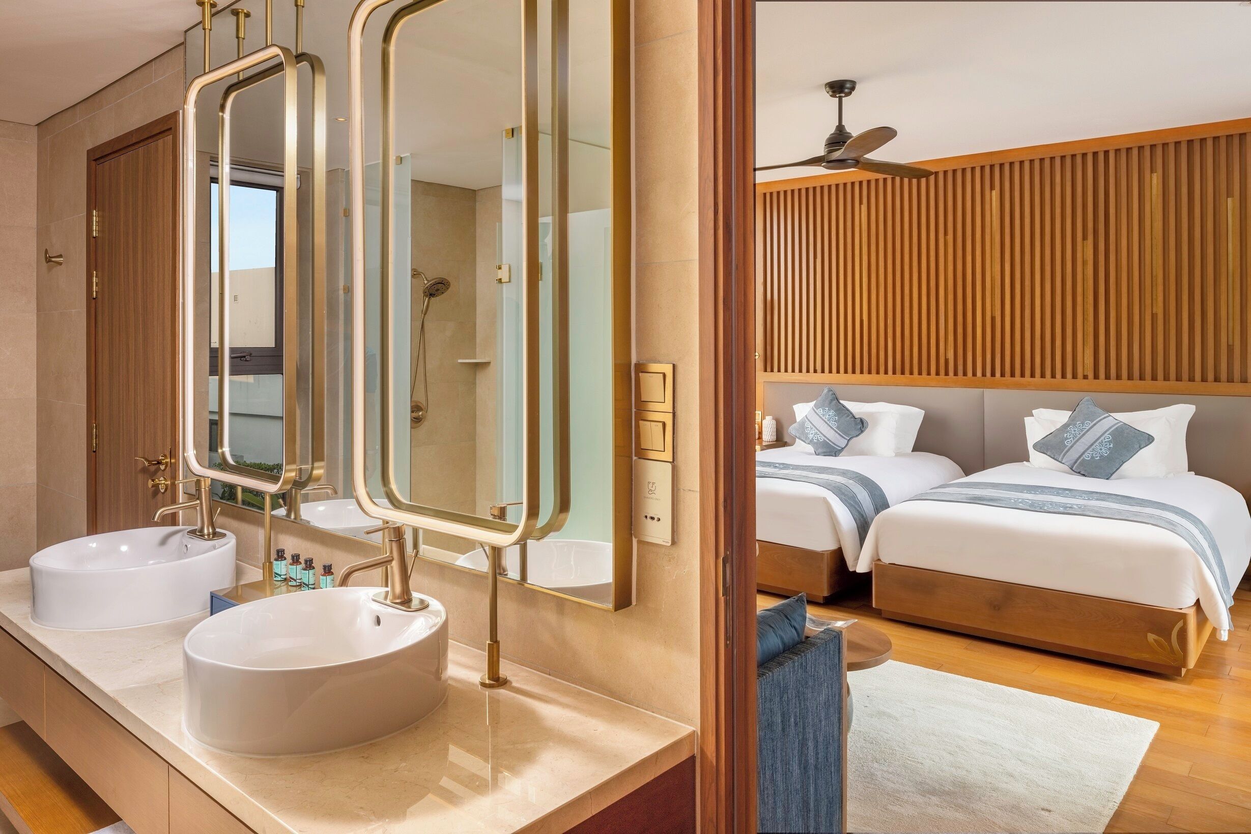 A modern bathroom with two sinks, a large mirror, and a wooden door.
