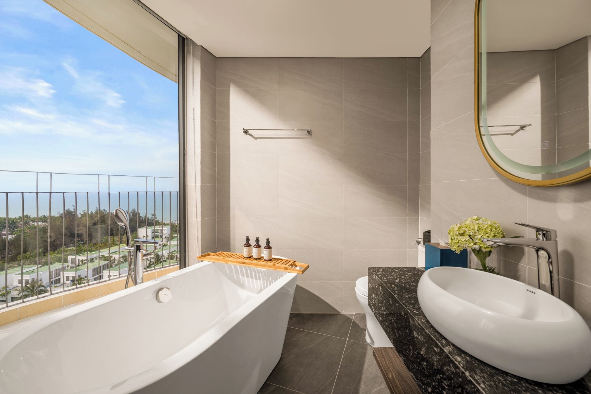 A modern bathroom with a large bathtub, a round sink, and a shower.