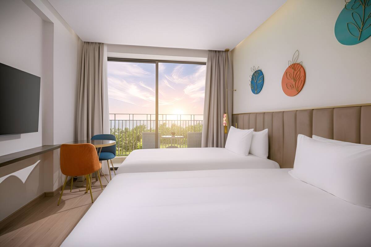 A hotel room with two beds, a TV, a balcony with a view, and decorative wall art.