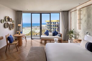 Una habitación de hotel moderna con un balcón amplio, una cama, un sofá y un comedor.