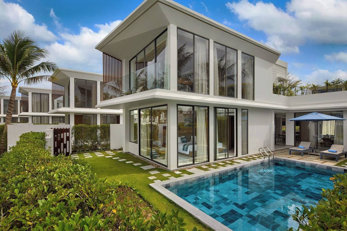 A modern two-story house with a swimming pool, large windows, and a well-maintained garden.